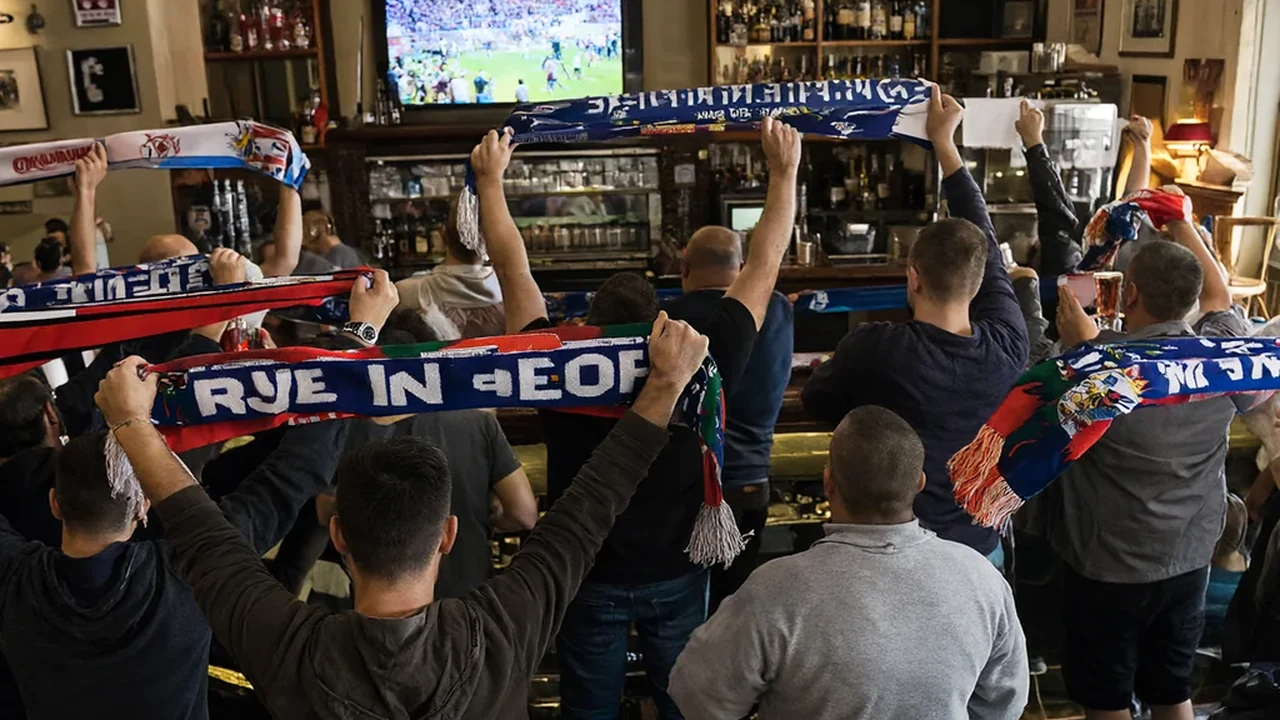 Italian football fans in a Boston bar watching Serie A on television with scarves raised
