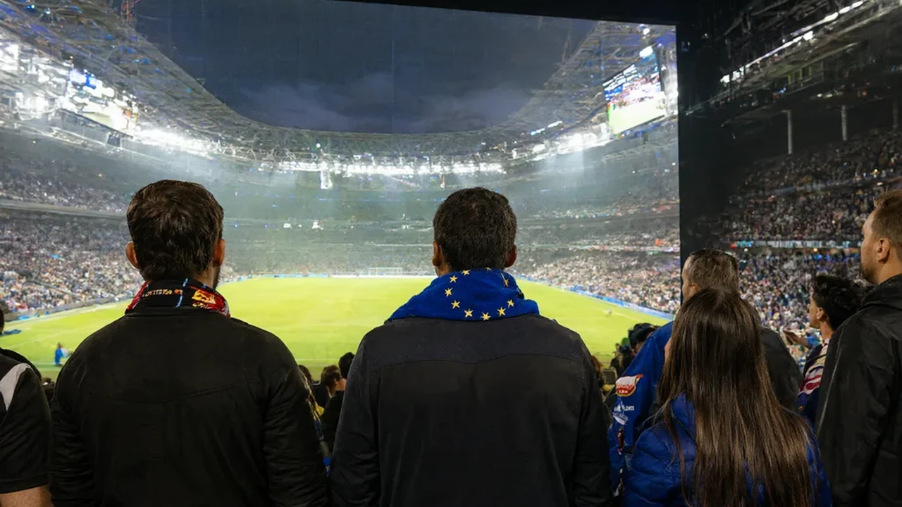 Friends in a pub watching a midweek European tie on a wall mounted screen, scarves on the table